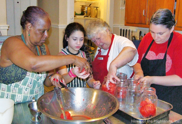 Photo by Jason Kaplan Emily Thomas shows Judi Leigh, Ilona Velasquez, and Louise DeCesare how to pack tomatoes into a jar, leaving little space for air, during a canning demonstration at The Grail on Saturday. 