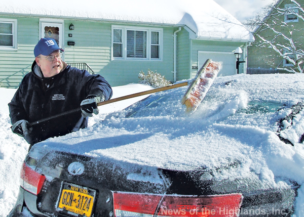 Rich Patterson sweeps snow off his car Friday morning following the snow storm. 