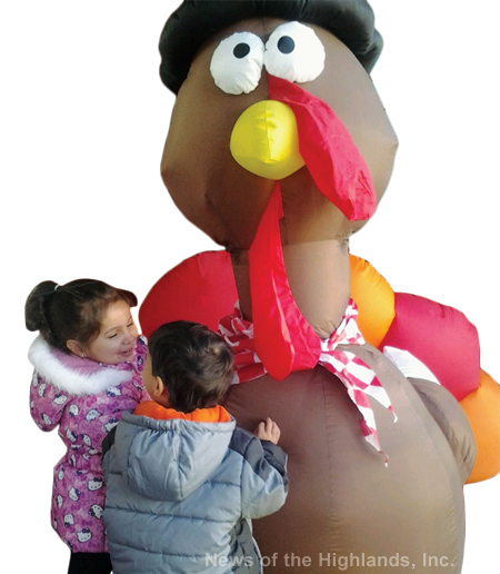 Photo by Suzanne Tagliaferro Twins, Lucy and James Darro, age 3, stop to hug the inflatable turkey out on Main Street this past Thursday.