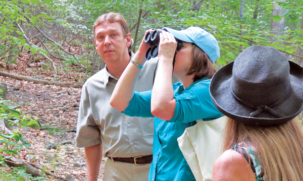 Contributed photo During a June 4 hike through Black Rock Forest, Erin Crotty of the New York Audubon Society aims her binoculars at a bird flying overhead. With her is Dr. Bill Schuster of the Black Rock Forest Consortium.