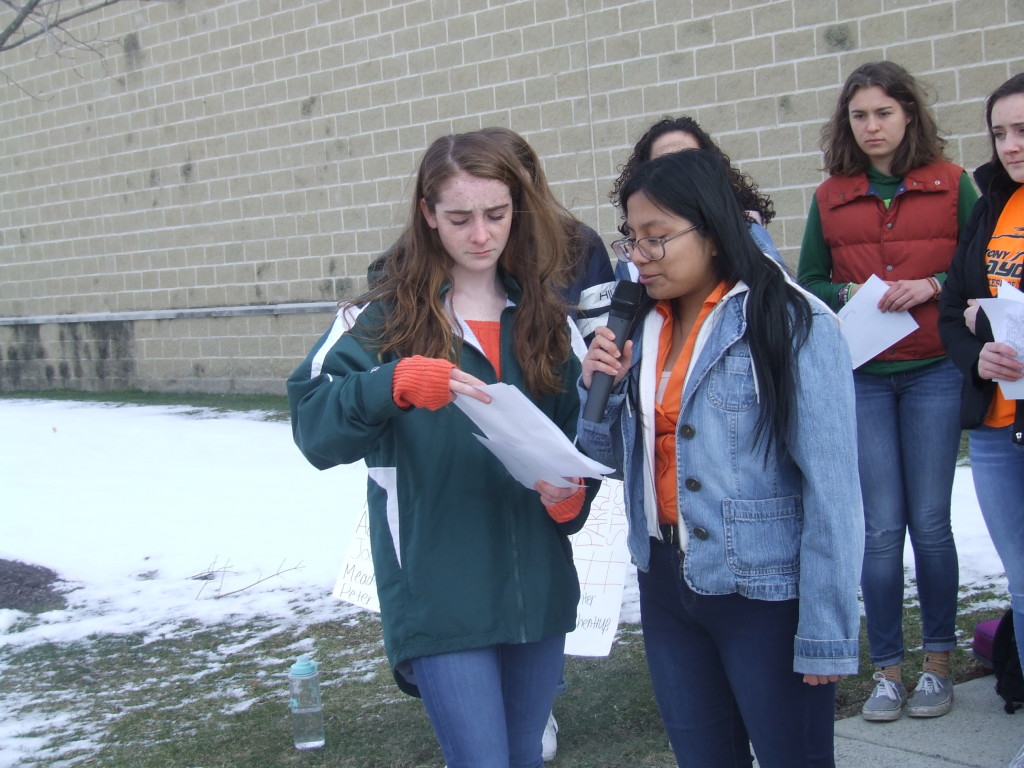 With the wind gusting, it was hard for Ana Martinez (right) to hold both the microphone and her speech. So Claire Kelly held the written statement for her. 