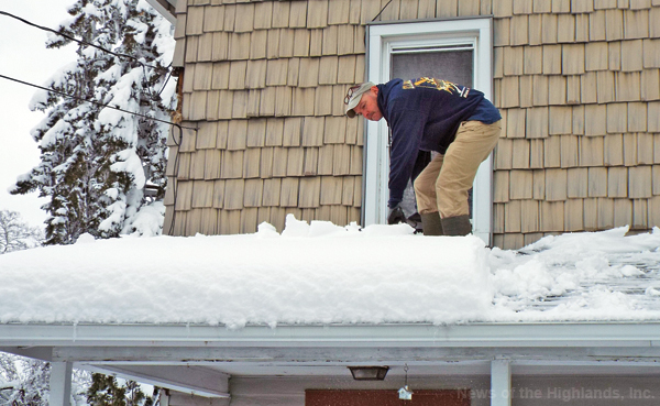 Photo by Jason Kaplan - Michael Brown removes snow from the roof of his mother’s house following last week’s blizzard. The storm dumped over a foot of snow in some areas. 