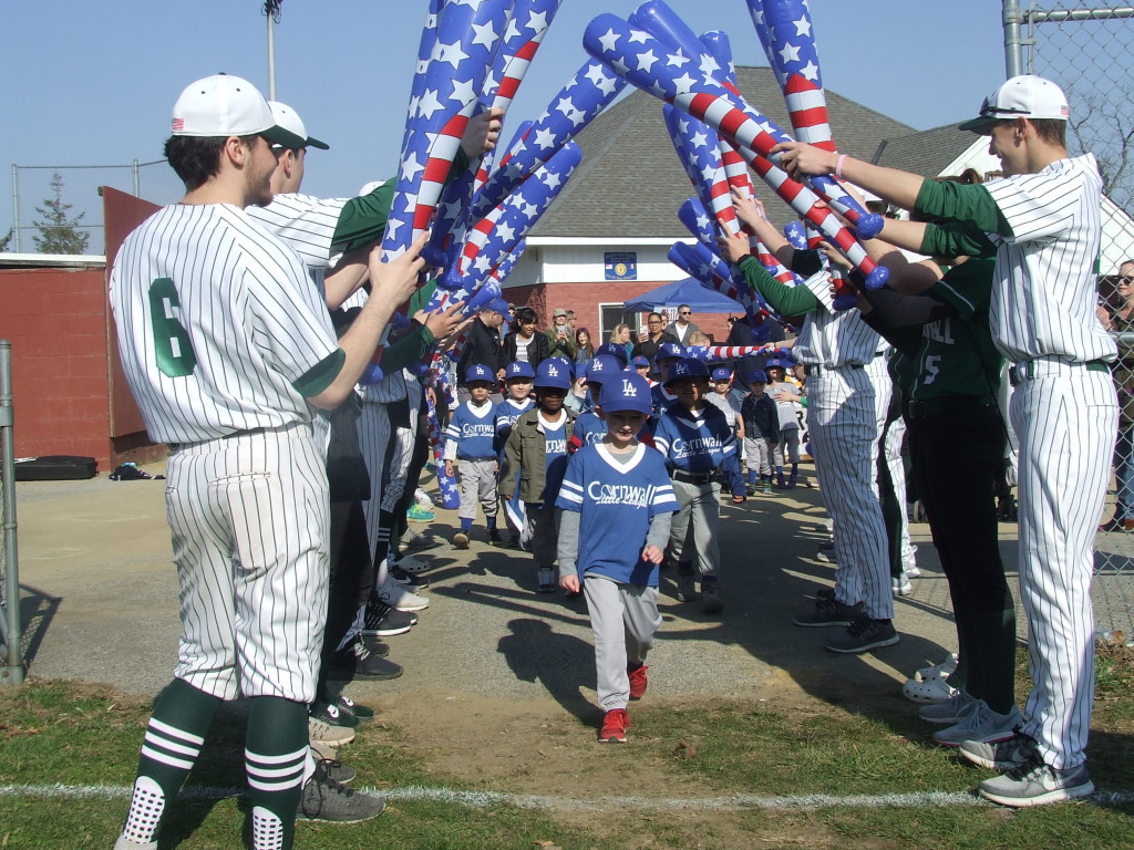 The varsity baseball and softball players formed an arch with inflatable bats. Little Leaguers marched under the bats and onto the field.
