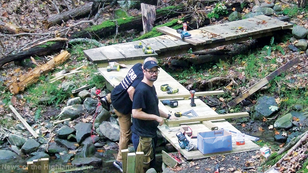 Anthony Cerra and Matthew Wilhelm (facing the camera) spent Oct. 7 building a bridge at the Wildlife Education Center. 